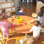 bambini che giocano in un tavolo roondo con vari giochi in un asilo nido